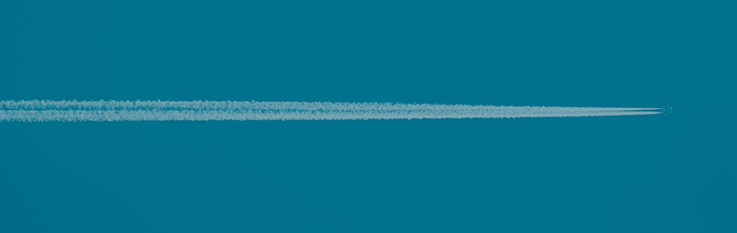 Airplane flying through a blue sky with a white contrail